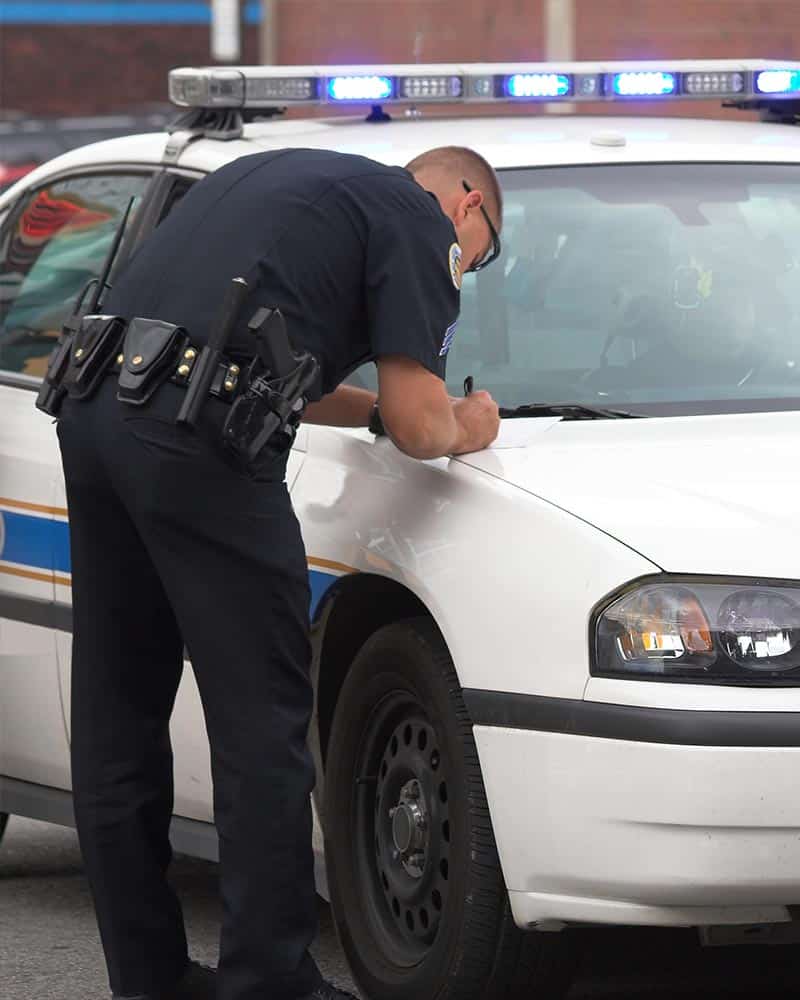 Police officer writing ticket on police car